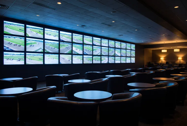 Dark lounge with chairs facing a wall of race screens